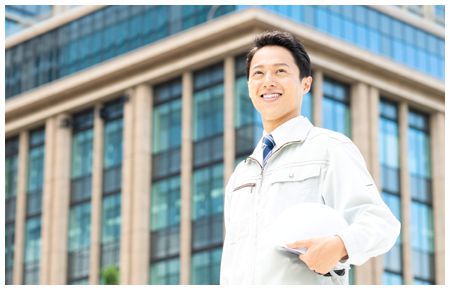 ビルの前でヘルメットを脇に抱える男性 ビルの前でヘルメットを脇に抱える男性